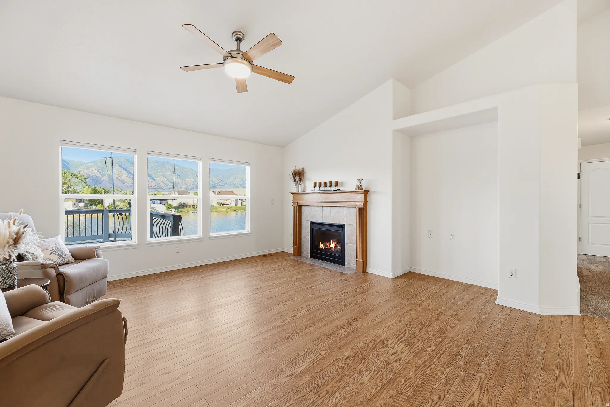 Spacious living area featuring wood-finish flooring, a vaulted ceiling, and an integrated fireplace with a tile surround and wood mantel
