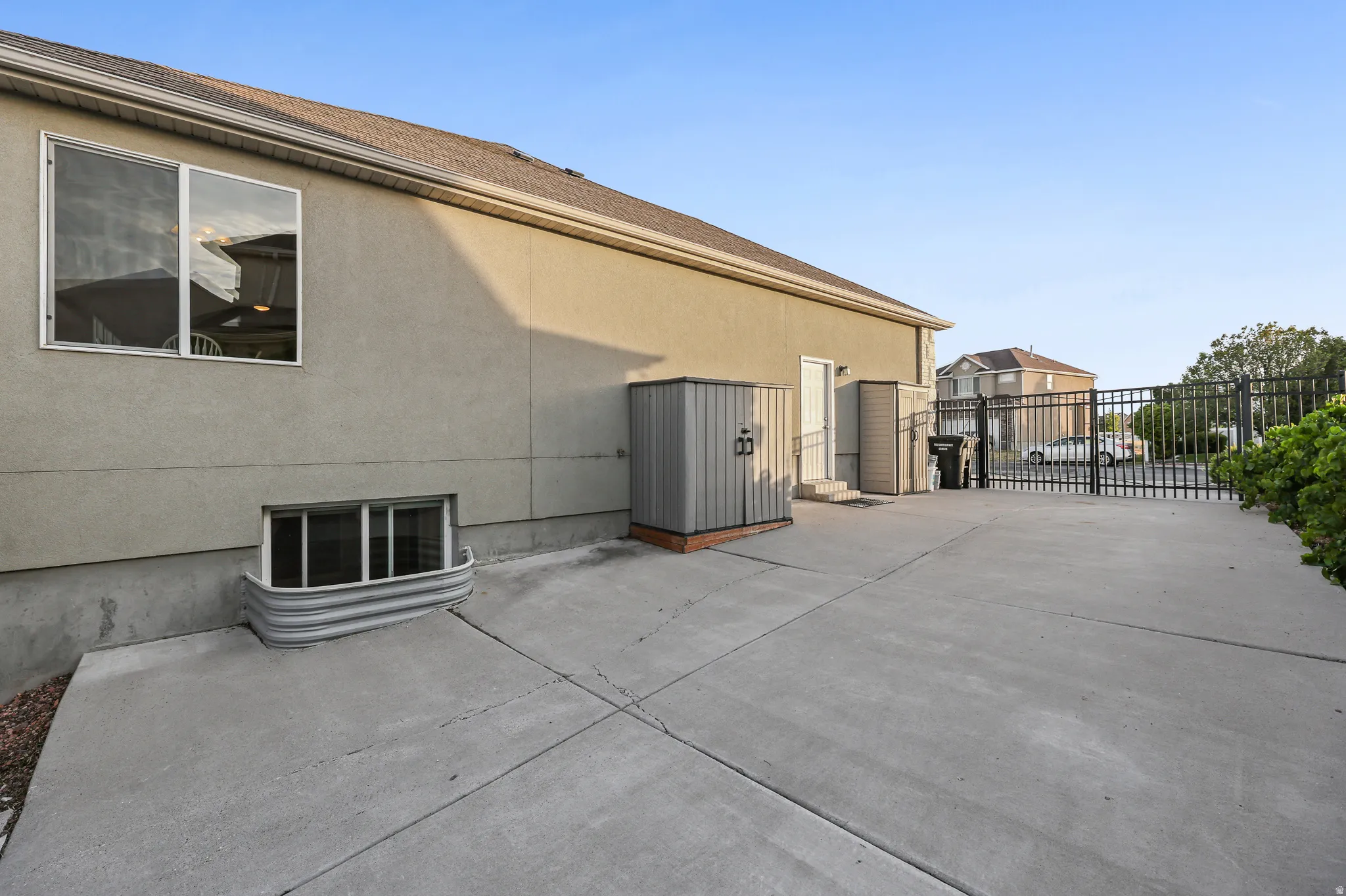 Spacious RV Parking -concrete driveway featuring a durable metal gate and a window well for basement access