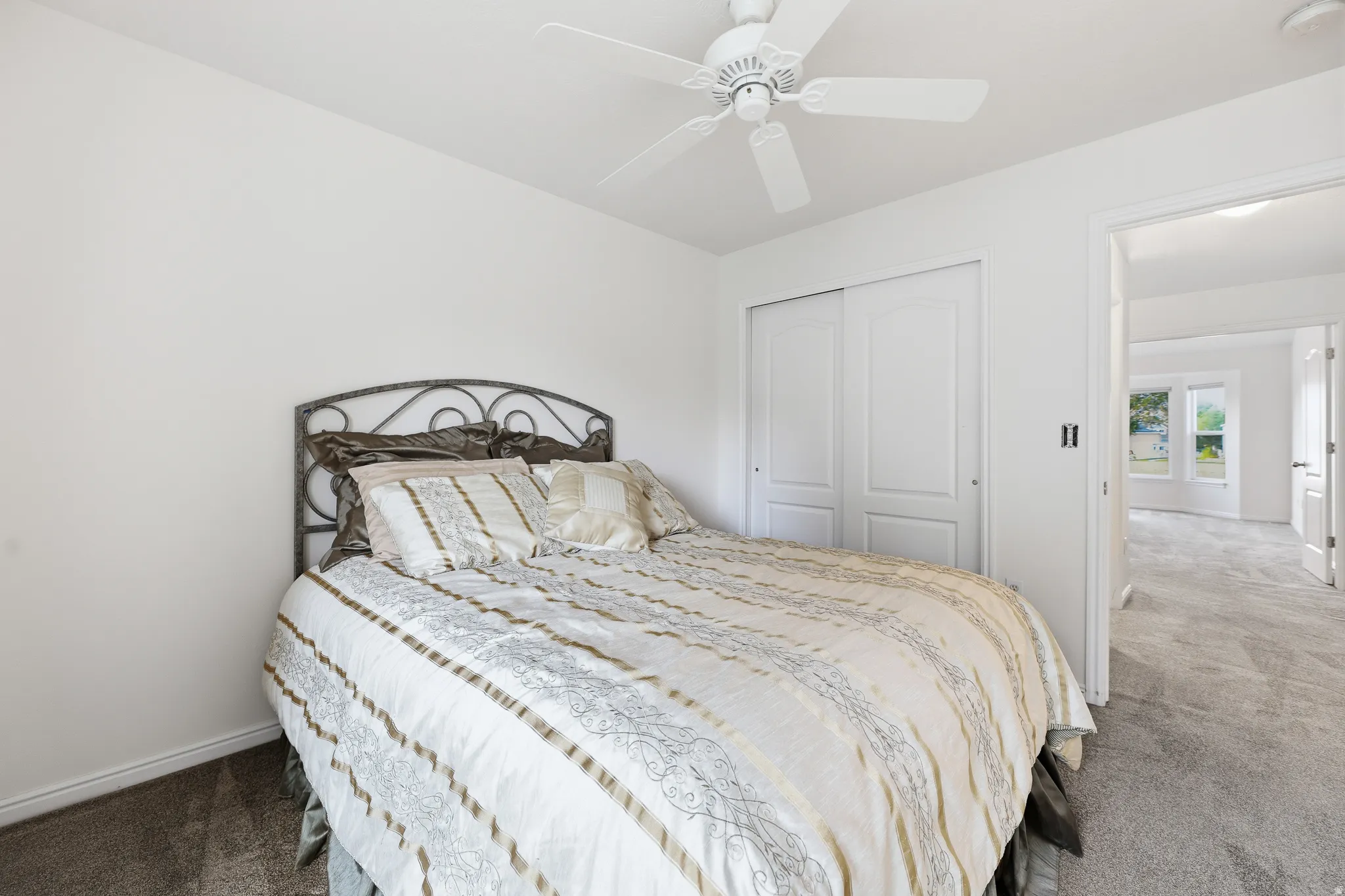 Bedroom featuring neutral wall paint, gray carpet, a ceiling fan, and sliding closet doors