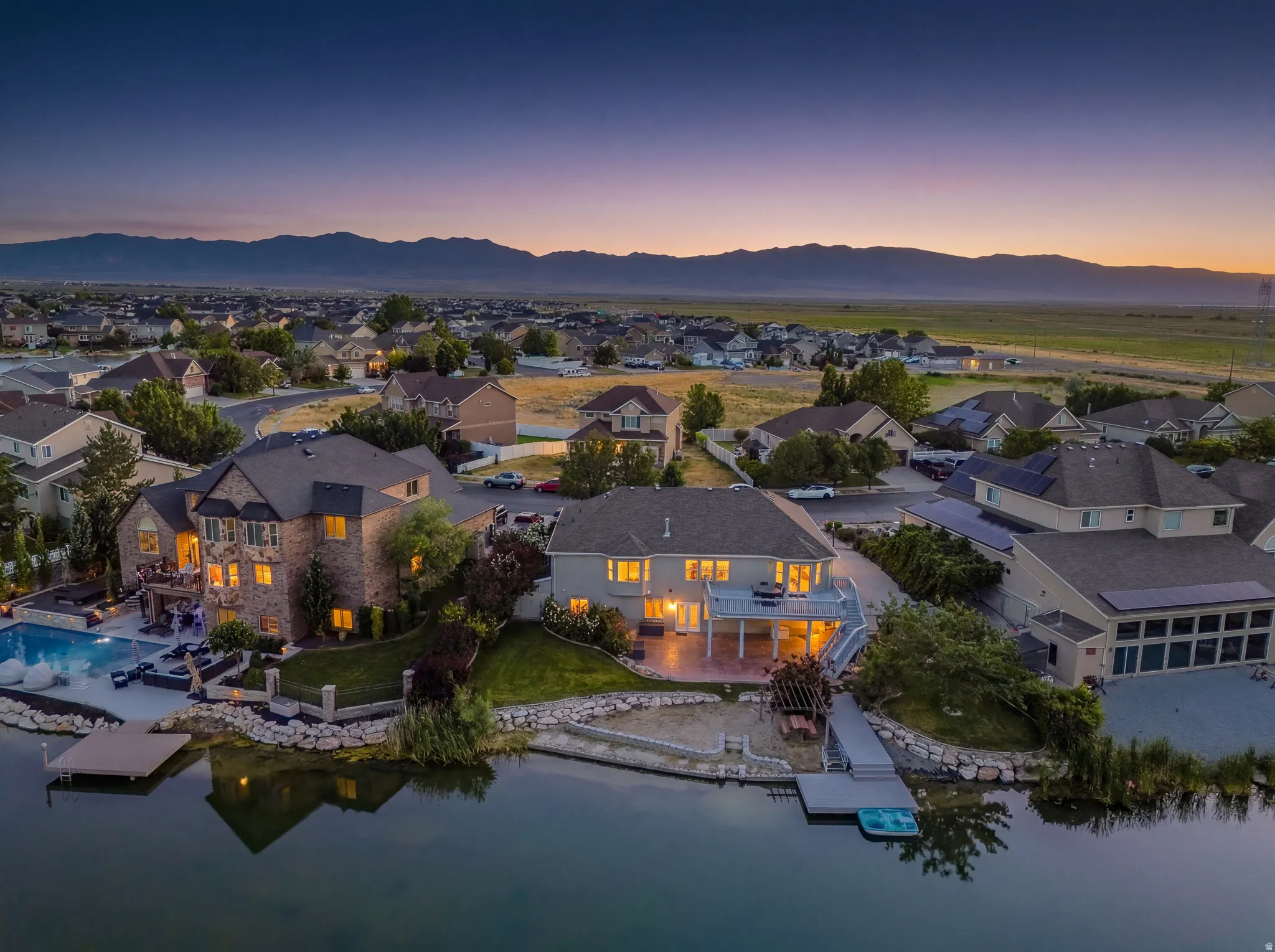 Waterfront property featuring a private dock, an expansive patio, and an in-ground swimming pool