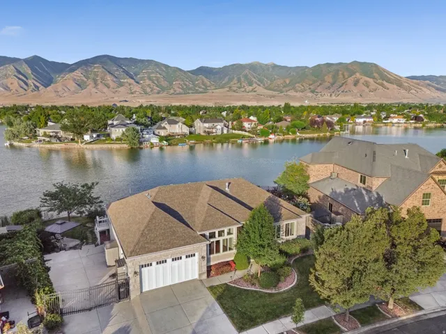 Waterfront property featuring a stone and brick facade, an attached two-car garage, and a gated driveway