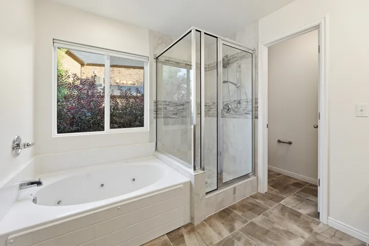 Primary Bath. Corner jetted soaking tub and glass-enclosed shower with tile surround