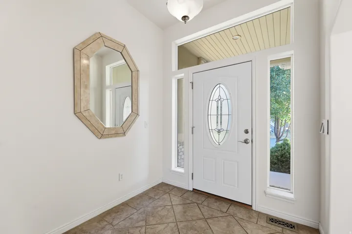 Entryway featuring a white door with an oval leaded glass insert, flanked by sidelight windows and topped with a transom window
