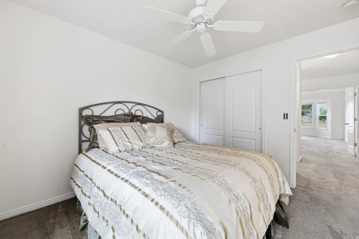 Bedroom featuring neutral wall paint, gray carpet, a ceiling fan, and sliding closet doors