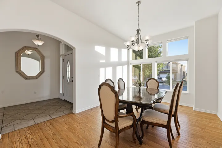 Dining area featuring vaulted ceilings, large windows, and wood-finish flooring