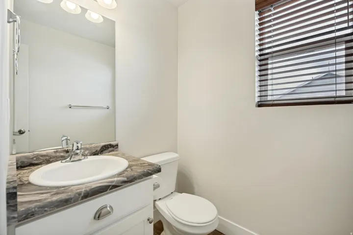 Bathroom featuring a white vanity with a patterned countertop, chrome faucet, and integrated sink