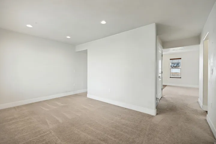 Spacious carpeted room featuring recessed lighting and white baseboards