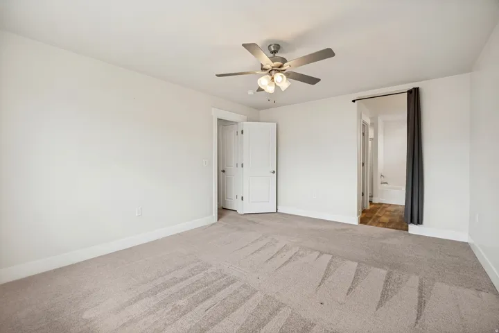 Neutral-toned carpeting extends throughout this room, featuring a ceiling fan with integrated lighting