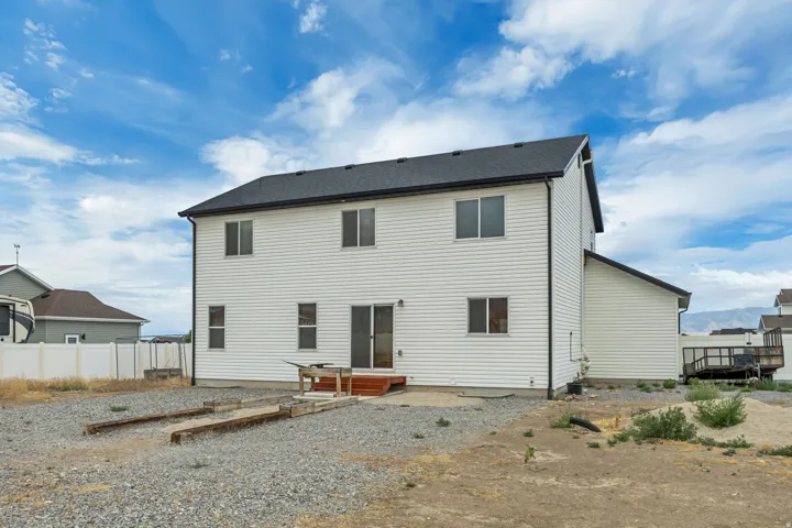 Rear exterior showcasing white siding, a dark shingle roof, and multiple windows
