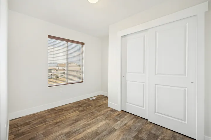 Bright room featuring wood-finish flooring, white baseboards, and a window with blinds