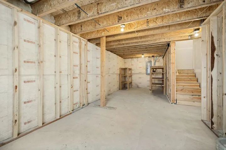 Unfinished basement space featuring exposed wood joists and subflooring, concrete floor, and partial wall framing