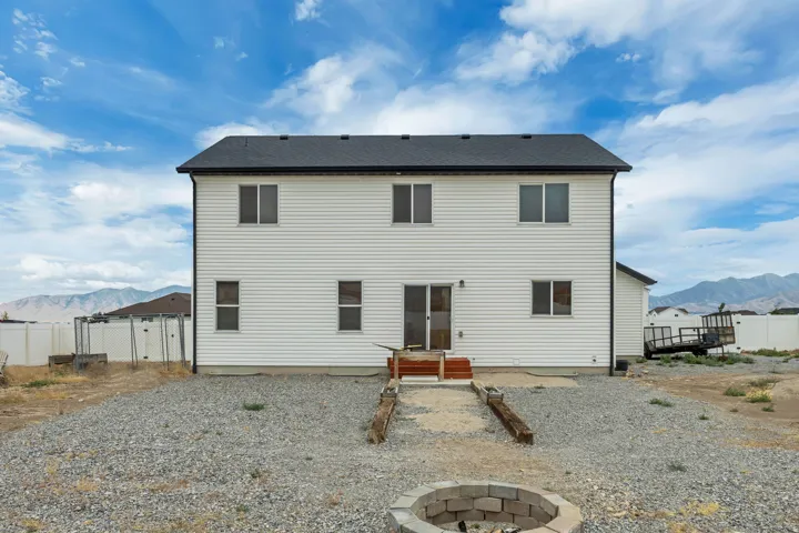 Rear exterior featuring white horizontal siding and a dark shingle roof