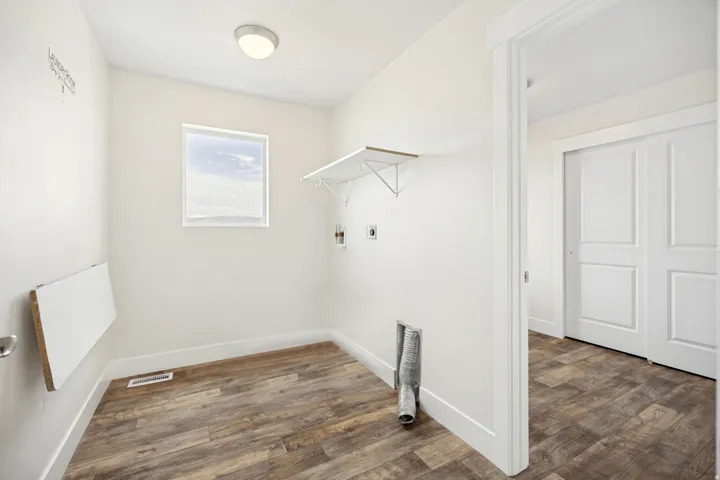 Dedicated utility room featuring wood-finish flooring, a wall-mounted folding surface, a window, and a ceiling-mounted light fixture