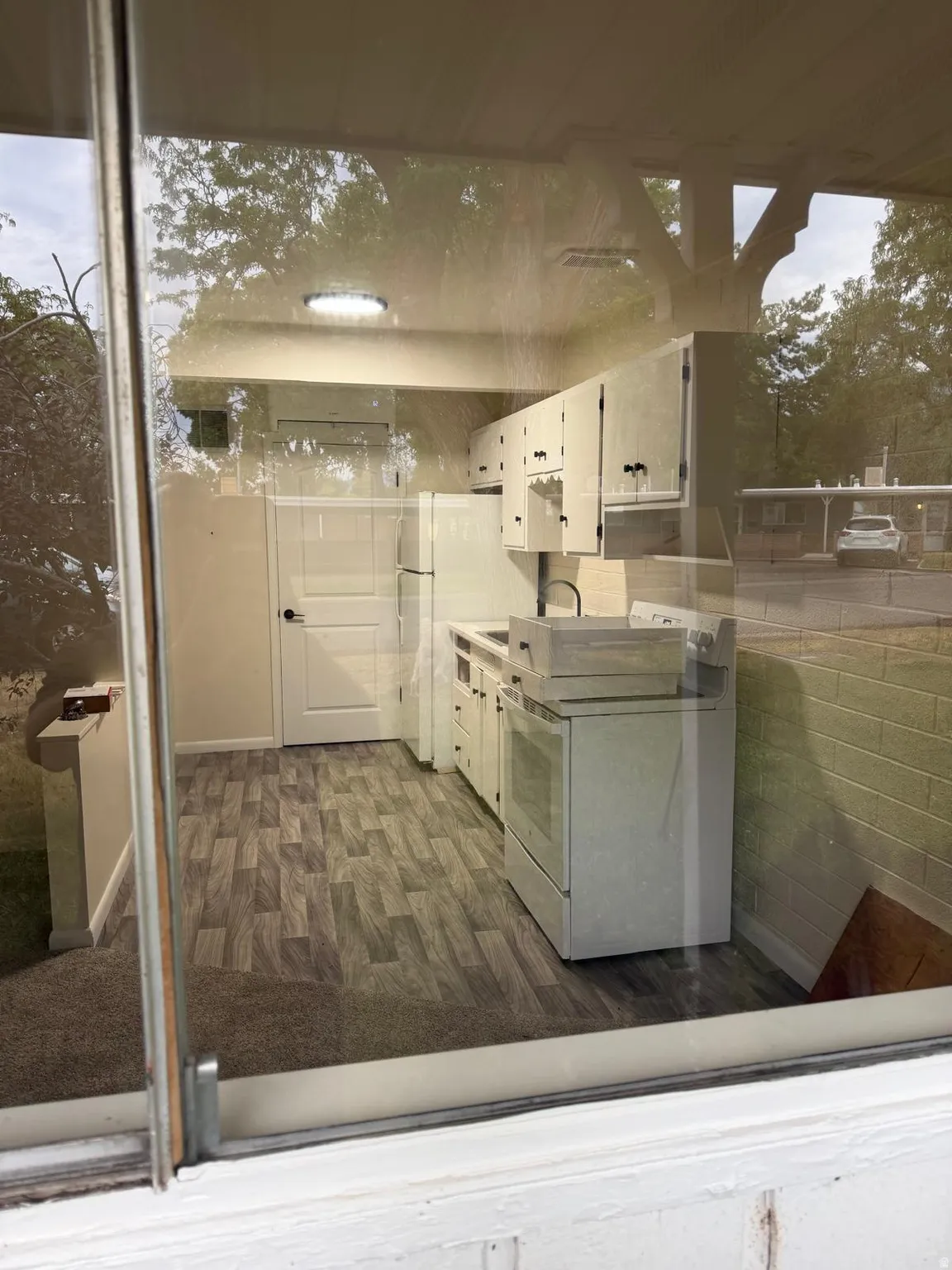 Compact kitchen featuring wood-finish flooring, white cabinetry, and white appliances