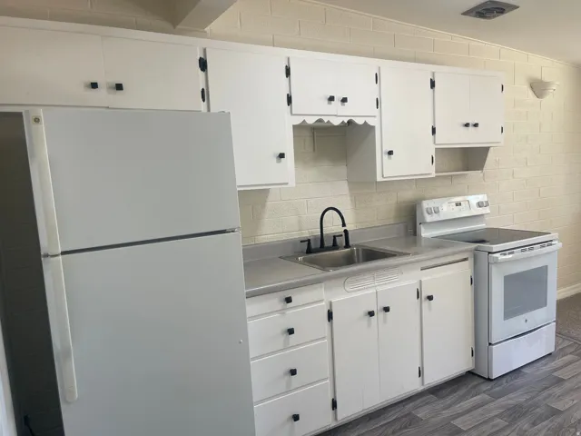 White cabinetry, stainless steel sink, wood-finish flooring, white refrigerator, and white electric range