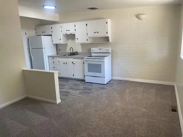 Kitchenette featuring white cabinetry, gray countertops, and a full suite of white appliances