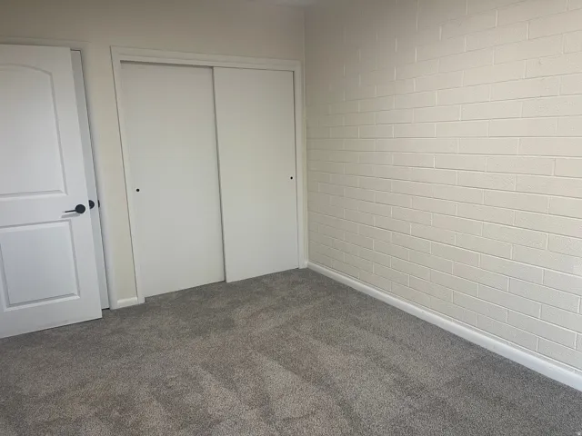 Neutral gray carpeting paired with a white brick-patterned wall