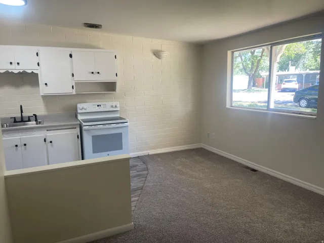Kitchenette with white cabinetry, electric range, and laminate countertops