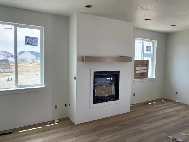 Fireplace with a light wood-finish mantel and a white surround