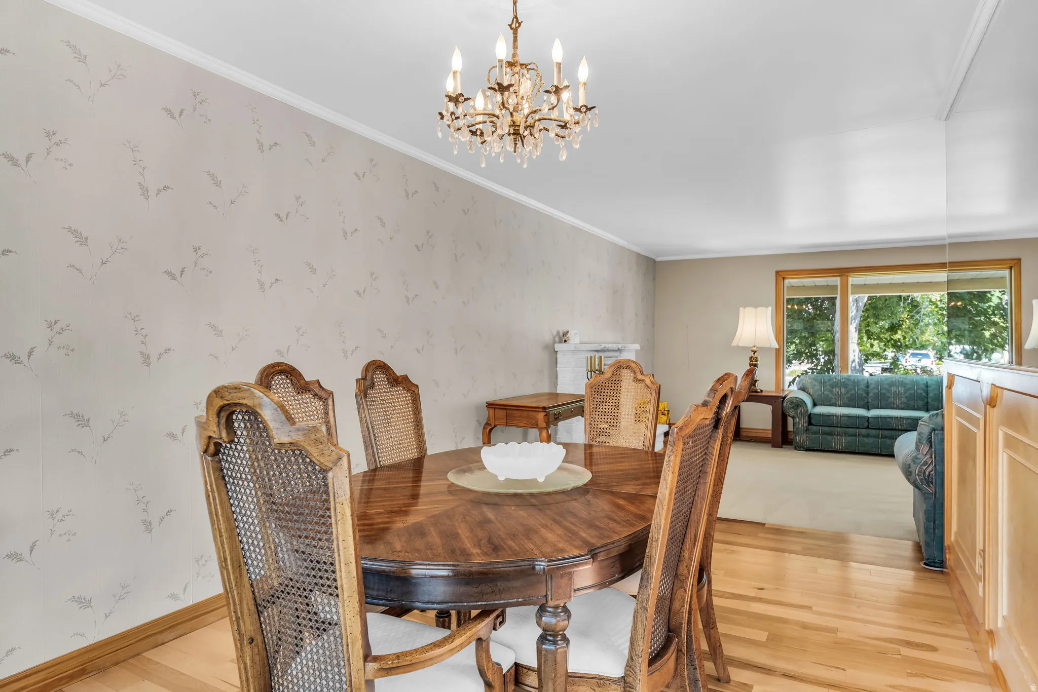 Formal dining area featuring wood-finish flooring, patterned accent wall, and a crystal chandelier