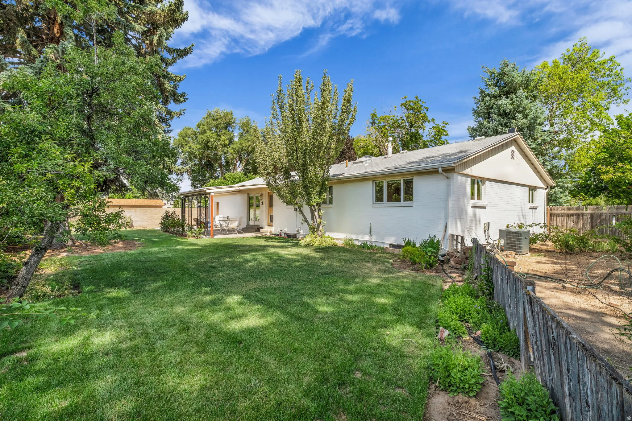 Spacious rear yard with expansive lawn, mature perimeter trees, and a private patio area
