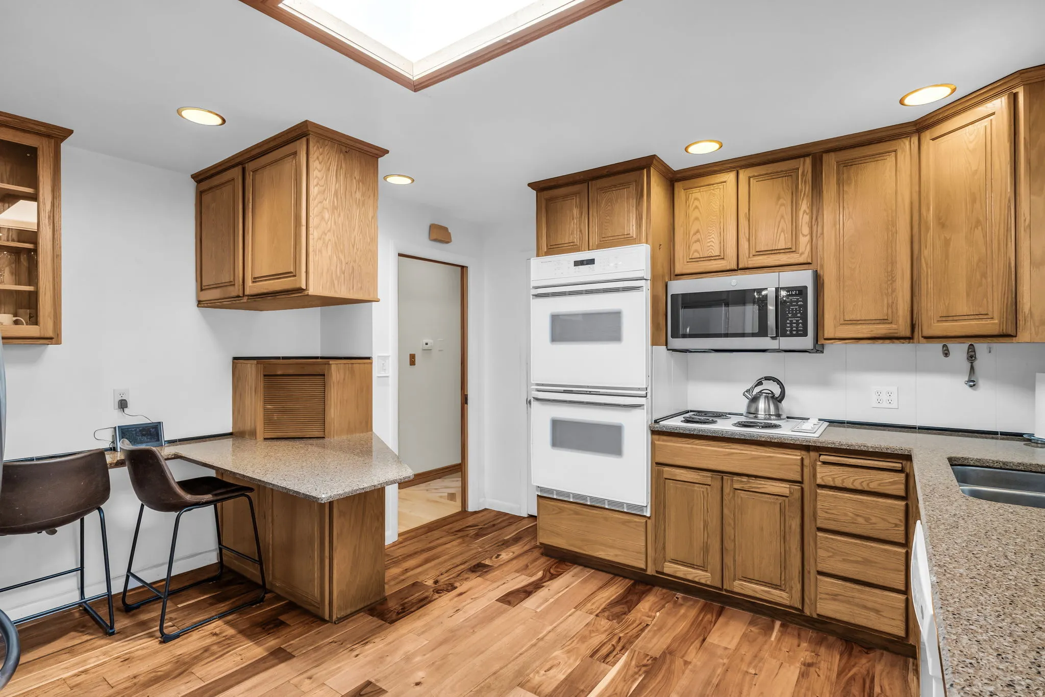 Kitchen featuring wood-finish flooring, recessed lighting, and a skylight