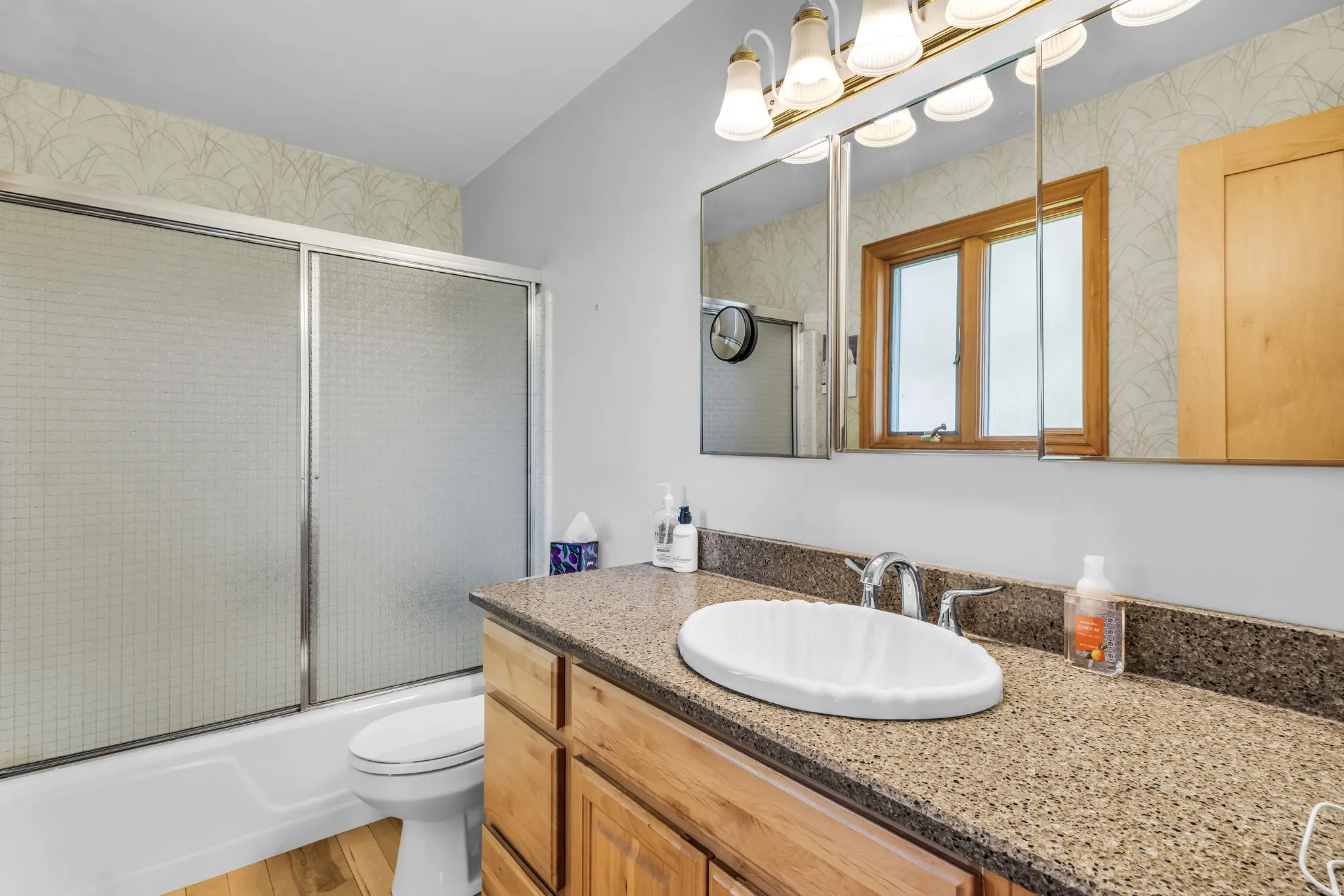Bathroom featuring a wood-finish vanity with a speckled countertop and an oval drop-in sink
