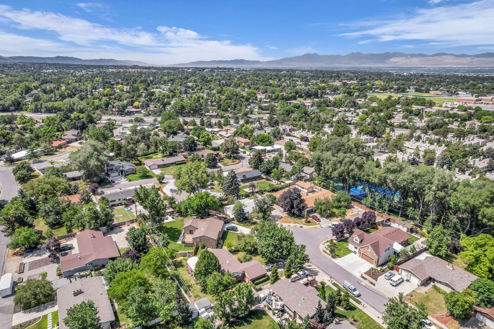 Aerial perspective showcasing a residential neighborhood with abundant mature trees and mountain scenery
