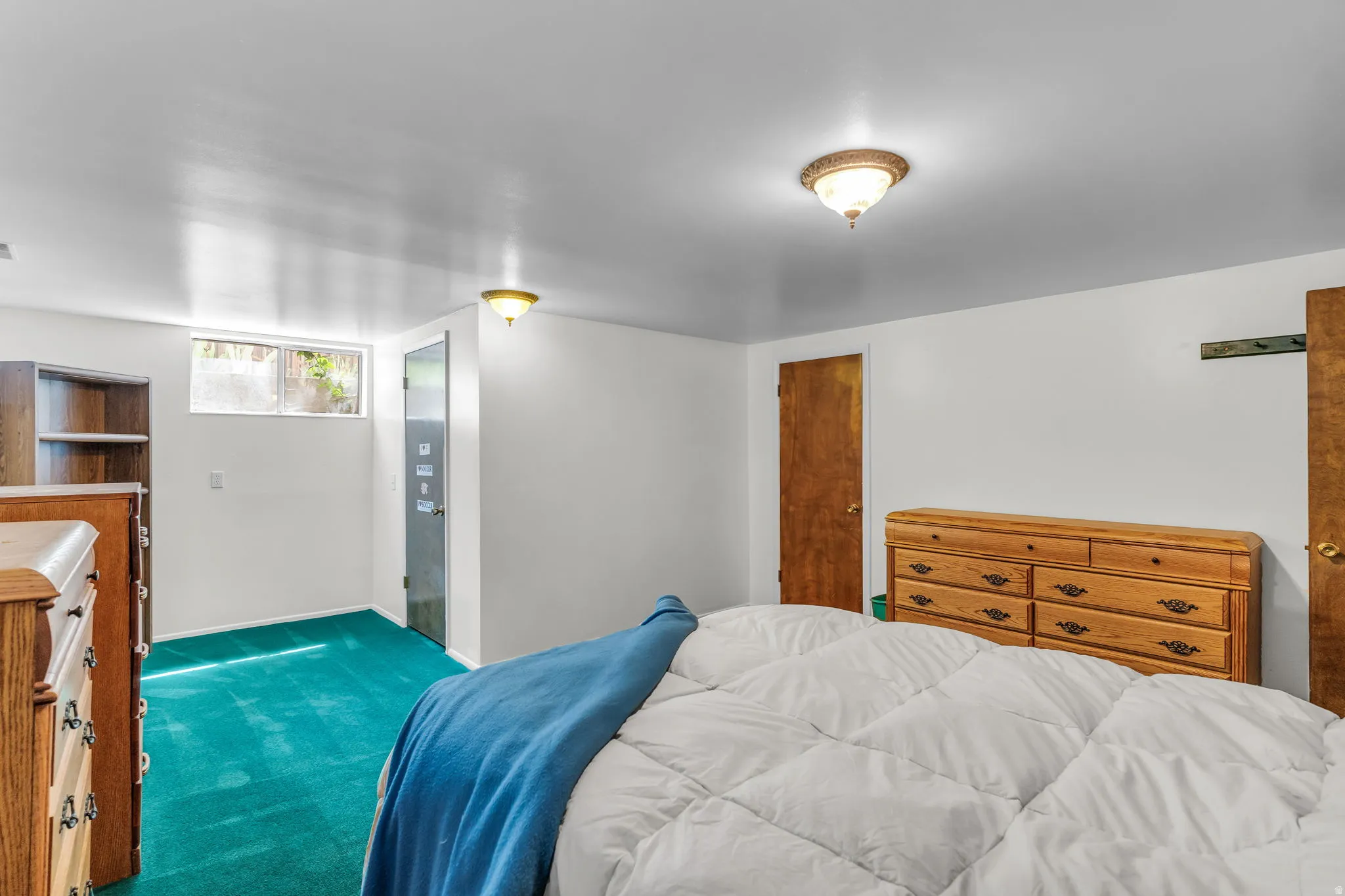 Carpeted bedroom featuring white walls, a single window, and a built-in wooden bookshelf