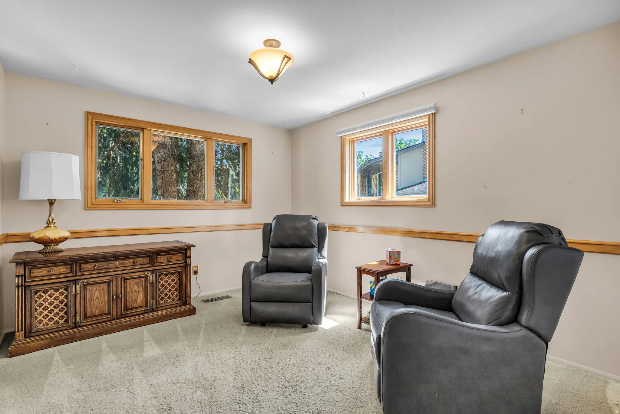 Bright room featuring neutral wall paint, light-toned carpeting, wood trim, and multiple windows