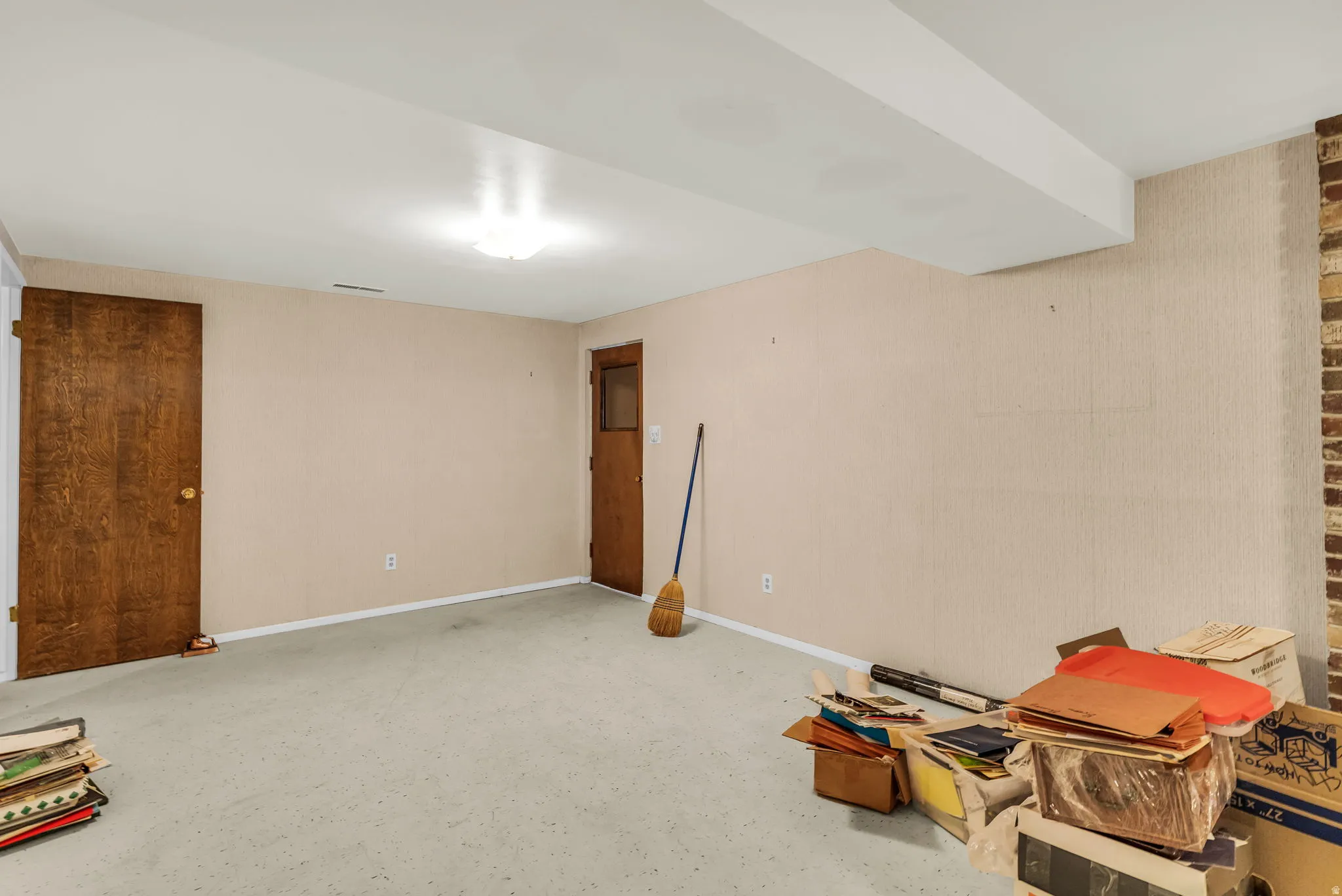 Spacious room with light-colored walls and carpeted flooring