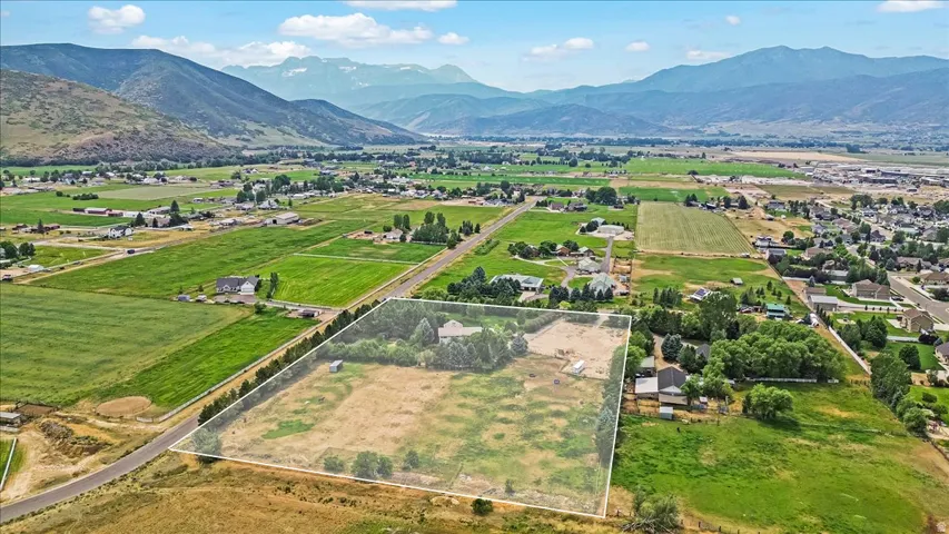 Expansive rural property featuring a primary residence, substantial open land, mature trees, and a mountain backdrop