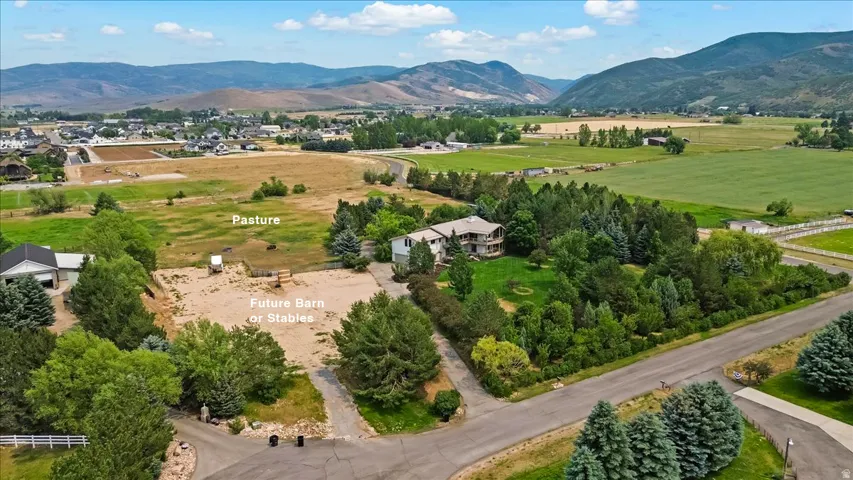 Expansive property featuring a large residence, surrounding mature trees, and substantial open land