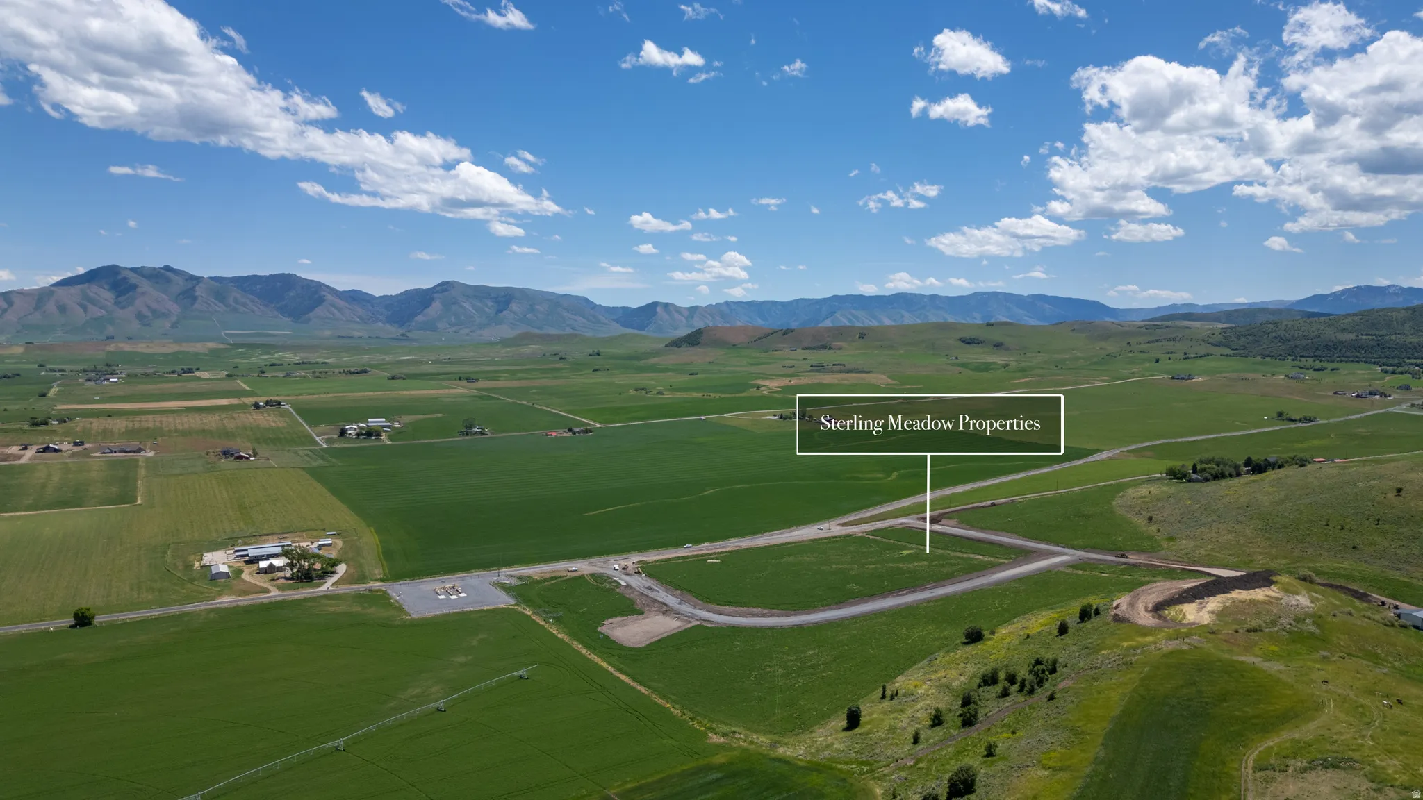 Expansive undeveloped land featuring rolling green hills and distant mountain ranges