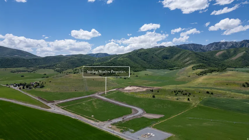 Expansive land parcels featuring established road infrastructure, verdant green fields, and distant mountain backdrops