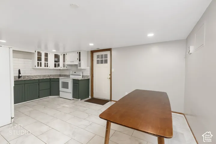 Kitchen area featuring dual-tone cabinetry, white subway tile backsplash, and granite-style countertops