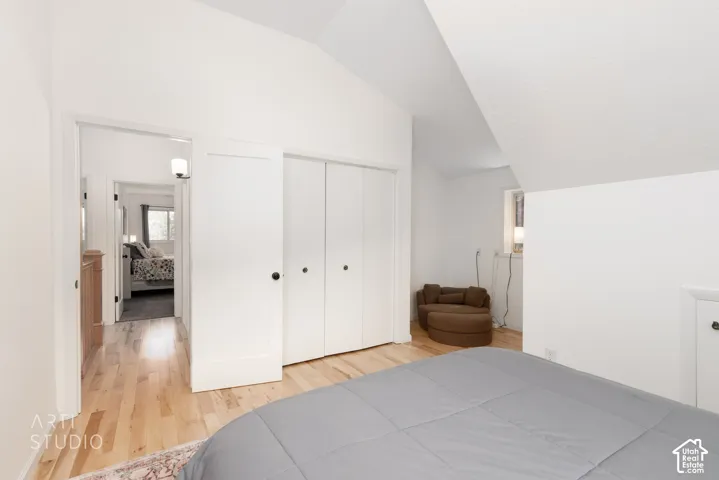 Hardwood-style flooring throughout, featuring a vaulted ceiling and bright white walls