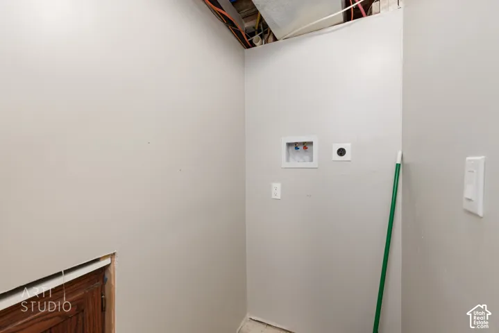 Dedicated laundry area featuring a wall-mounted washer hookup, dryer vent, and light gray painted walls