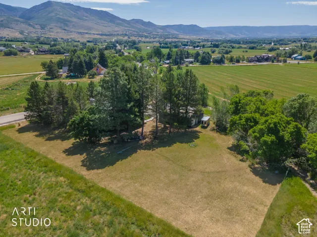 Expansive land parcel featuring mature trees, a clear building site, and distant mountain backdrops