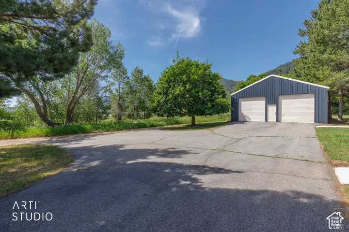 Blue metal-sided outbuilding featuring two garage doors and a single access door