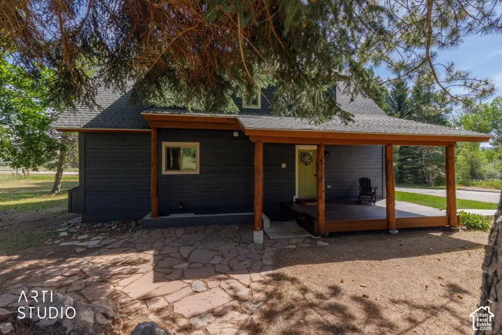 Charcoal siding exterior featuring a grey shingle roof and a spacious covered porch with natural wood posts and exposed beams