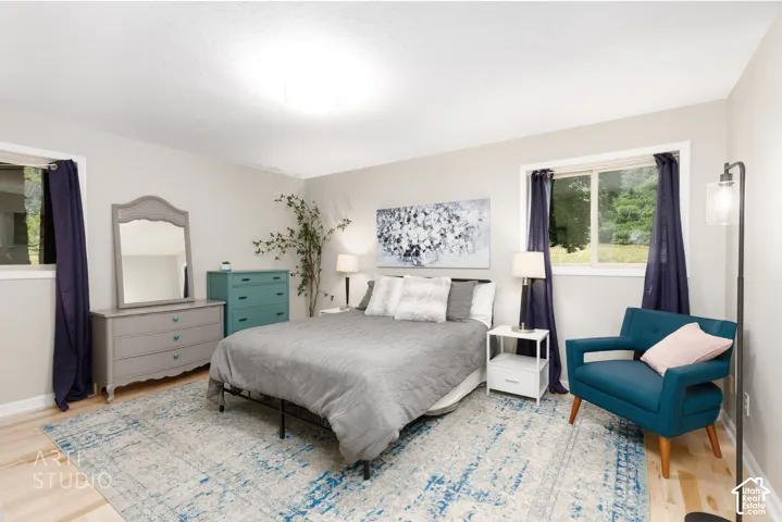 Spacious room featuring light wood-finish flooring, neutral wall tones, and two windows
