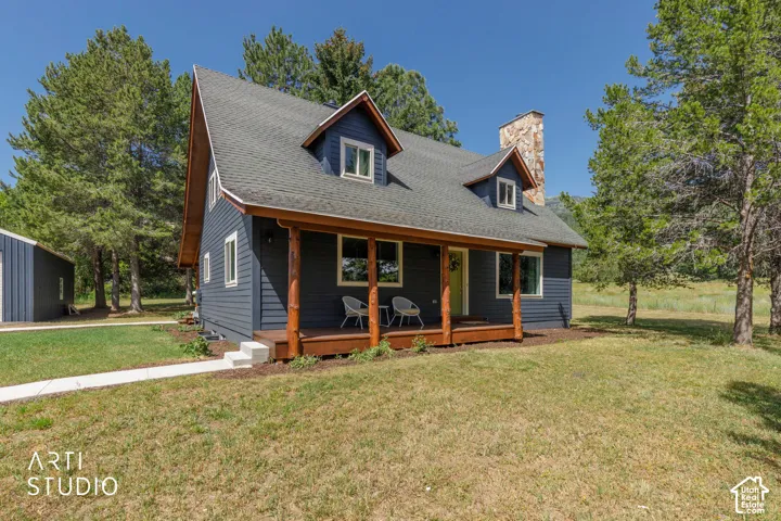 Charming residence featuring dark blue siding, a covered front porch with natural wood posts, and a prominent stone chimney