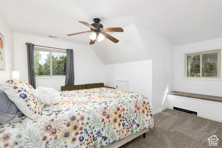 Carpeted room featuring a ceiling fan, two windows, and a built-in window bench