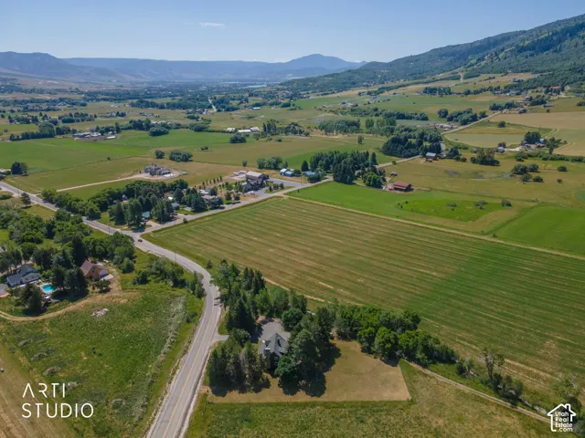 Expansive rural landscape featuring a single-family residence, mature trees, and agricultural fields