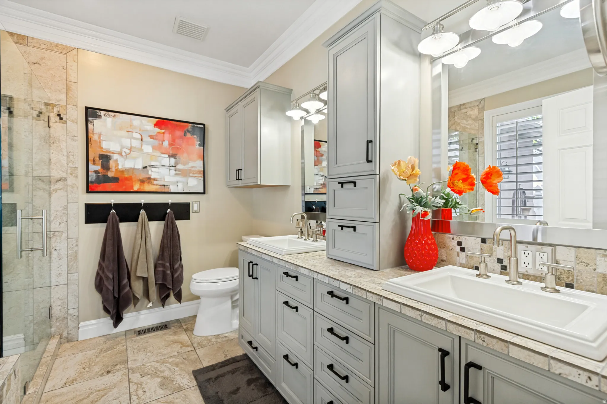 Bathroom featuring an expansive double vanity with light gray cabinetry, brushed nickel fixtures, and a tiled backsplash