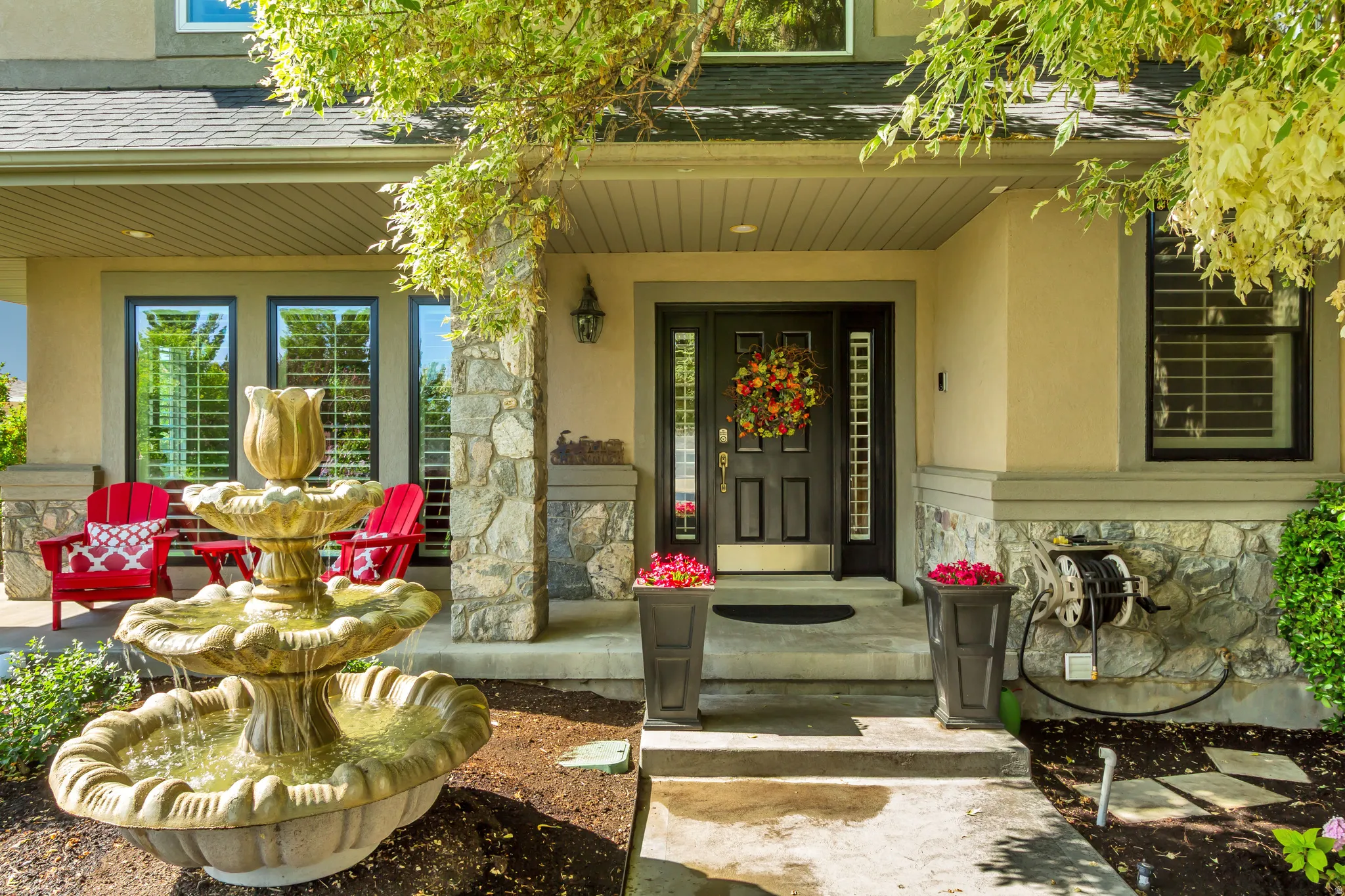 Front entry featuring a multi-tiered fountain, stone columns, dark paneled door, and side-light windows