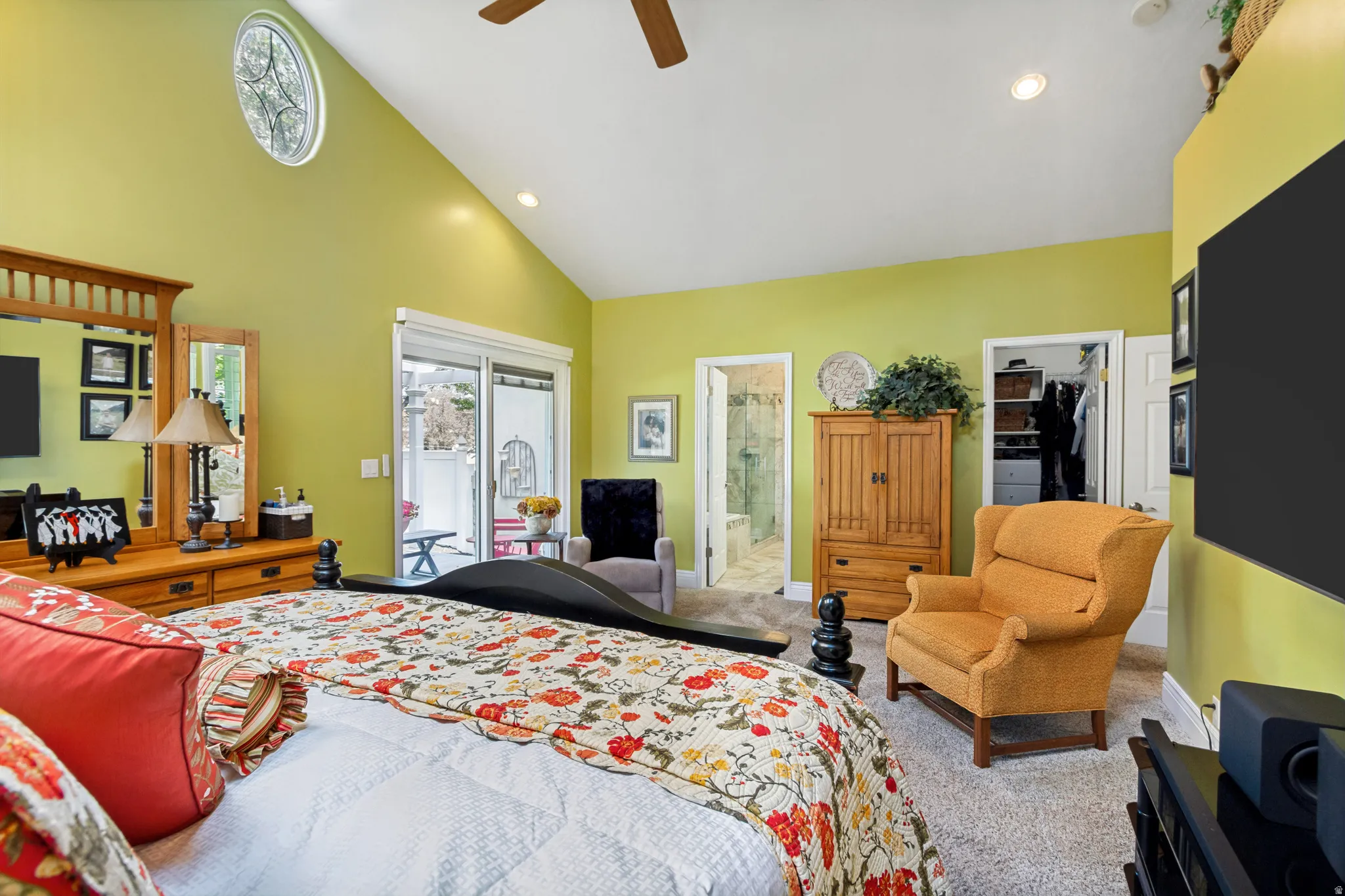 Spacious bedroom featuring vaulted ceilings, a prominent oval window, and soft carpet flooring