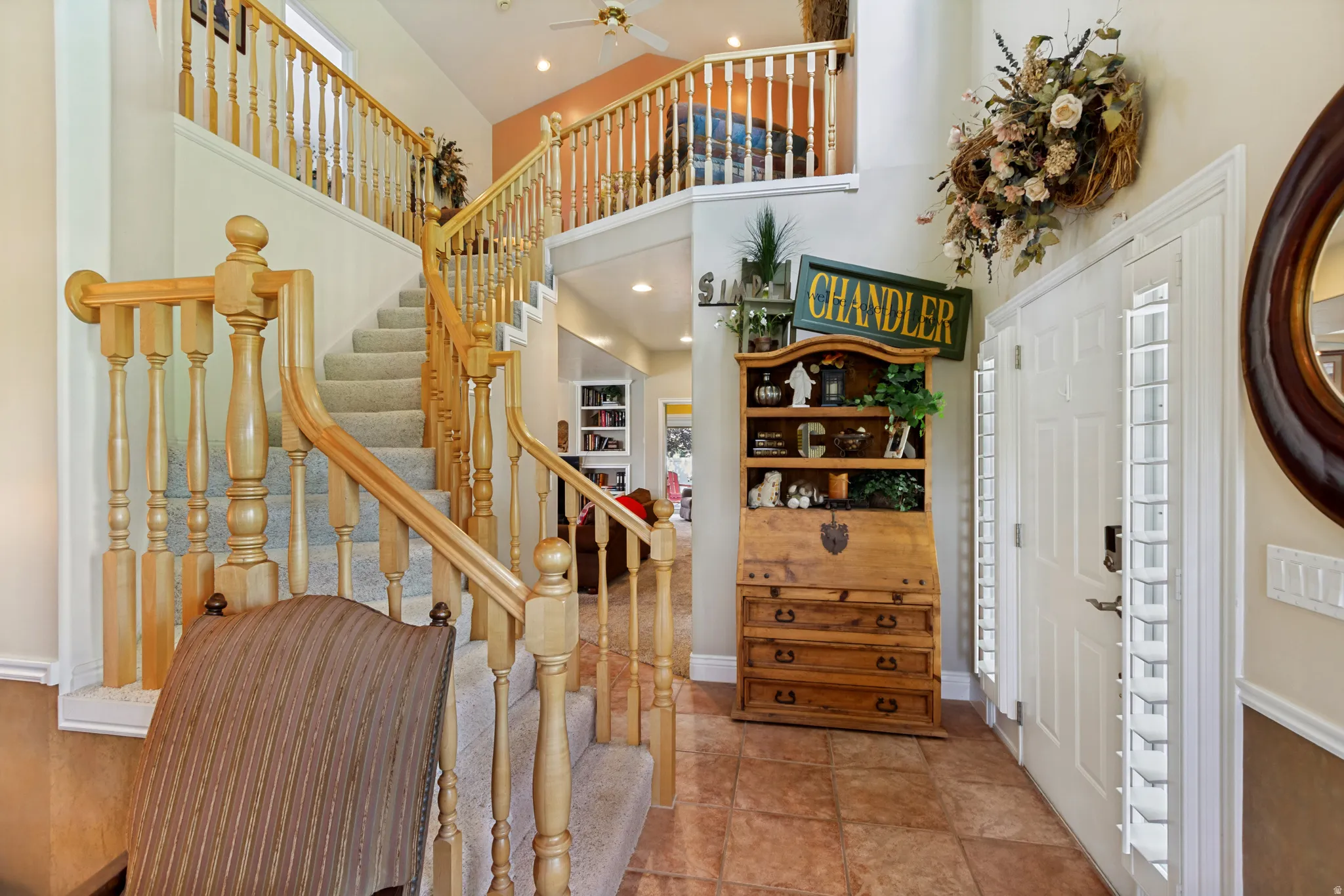 Two-story foyer featuring tile flooring, a multi-level staircase with carpeted treads, and wood banisters