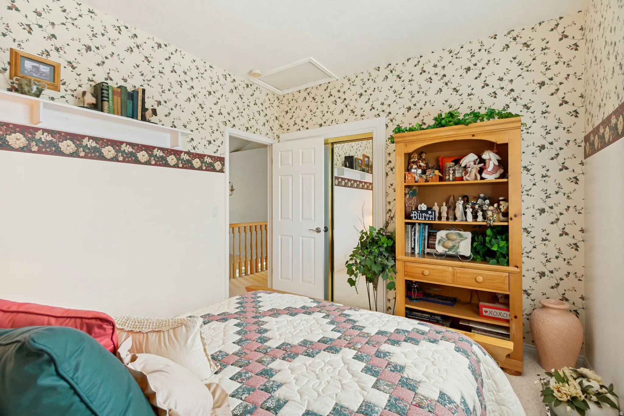 Room featuring floral wallpaper, white trim, and a built-in shelving unit